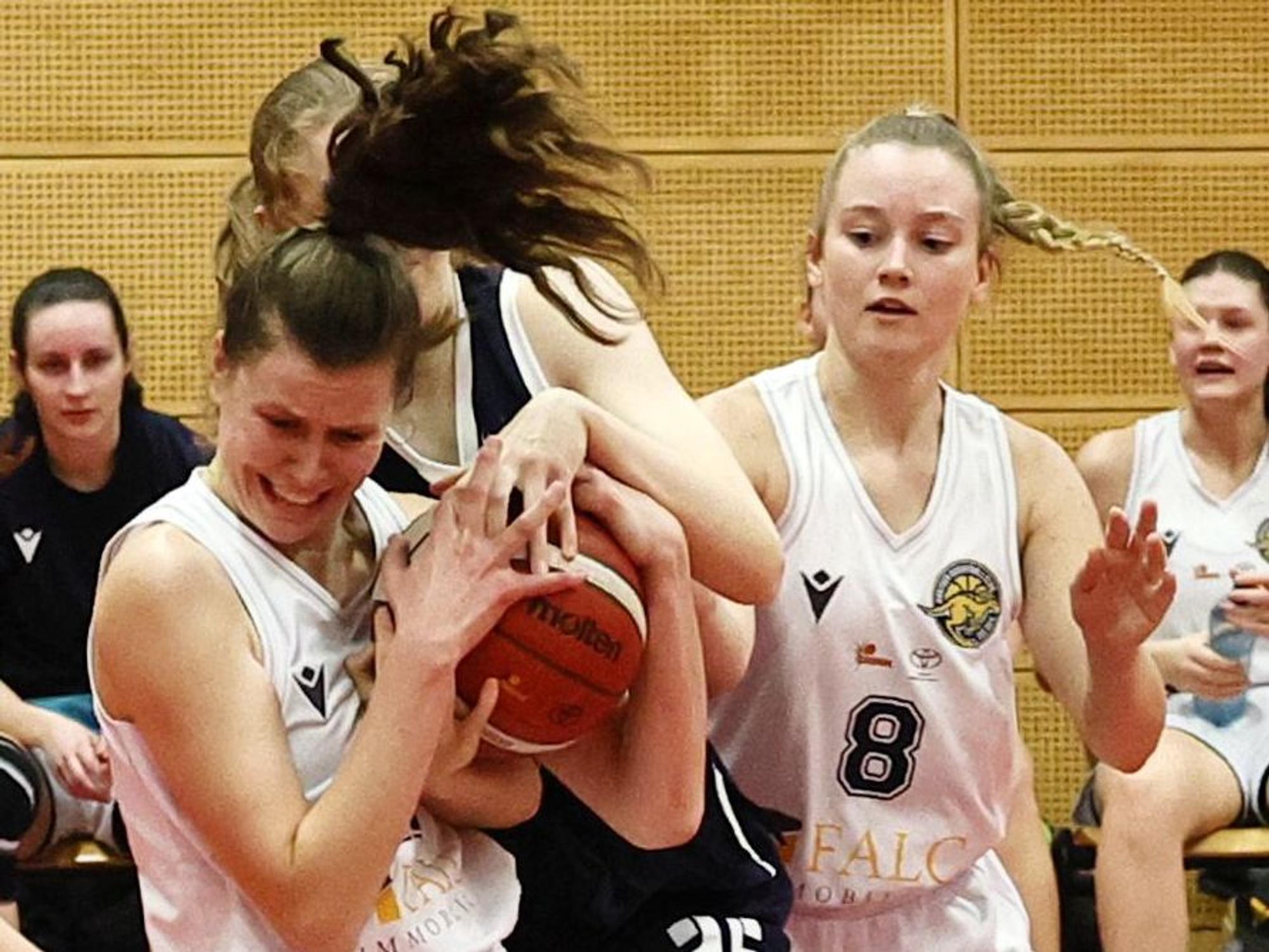 Das Foto zeigt zeigt eine Hürther Basektballerin, die im Zweikampf den Ball vor ihrer Oberhausener Gegenspielerin zupackend festhält.