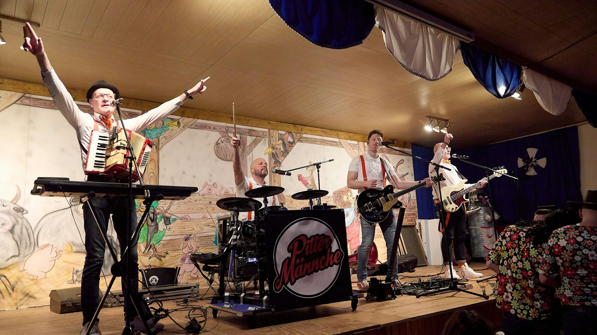 Vier Männer musizieren. Der Keyboarder, der Schlagzeuger und der Bassist recken ihre Arme in die Höhe.