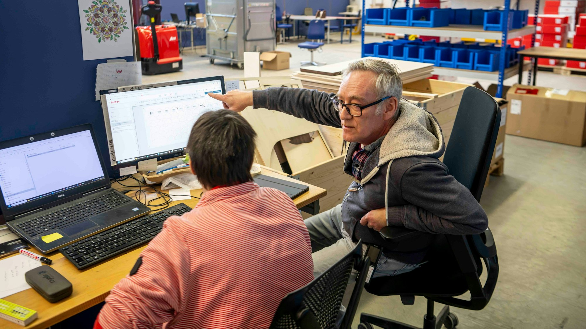 Ein Betreuer bespricht mit einem Mitarbeiter am PC die nächsten Schritte.