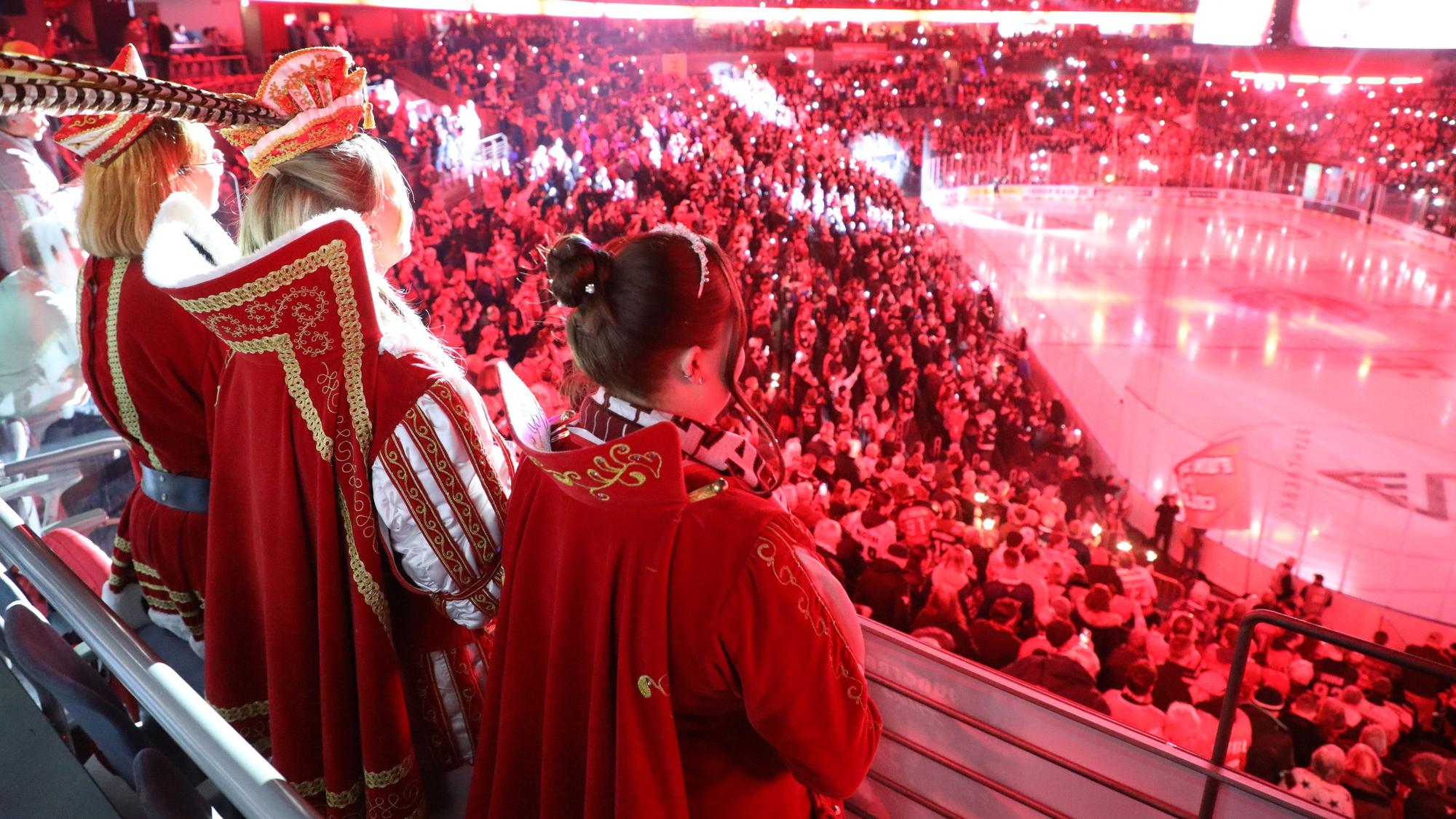 Das Dreigestirn Oberodenthal steht auf einem Rang vor einer Loge in der Kölner Lanxess-Arena und schaut ein KEC-Eishockeyspiel.