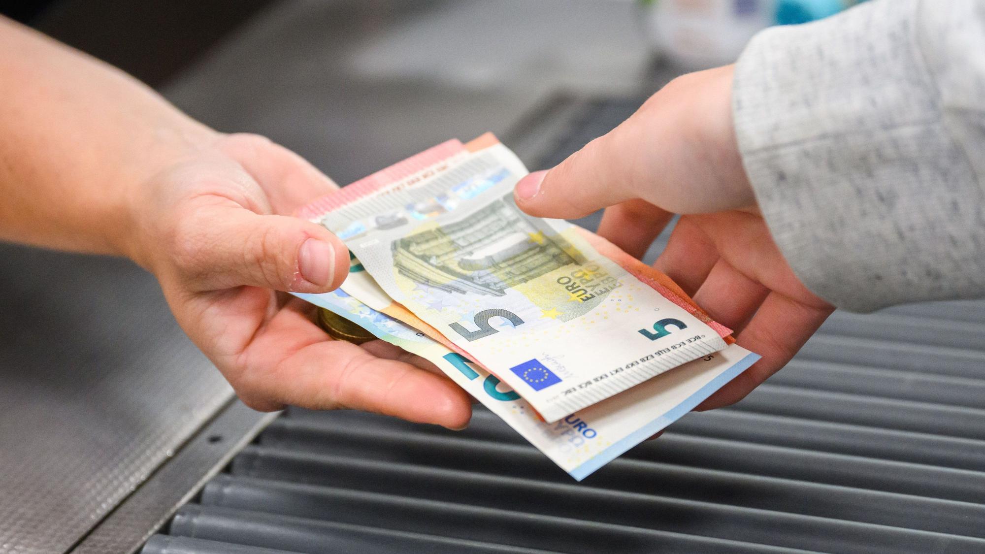 Eine Kassiererin gibt einer Kundin Wechselgeld an der Kasse eines Supermarktes.