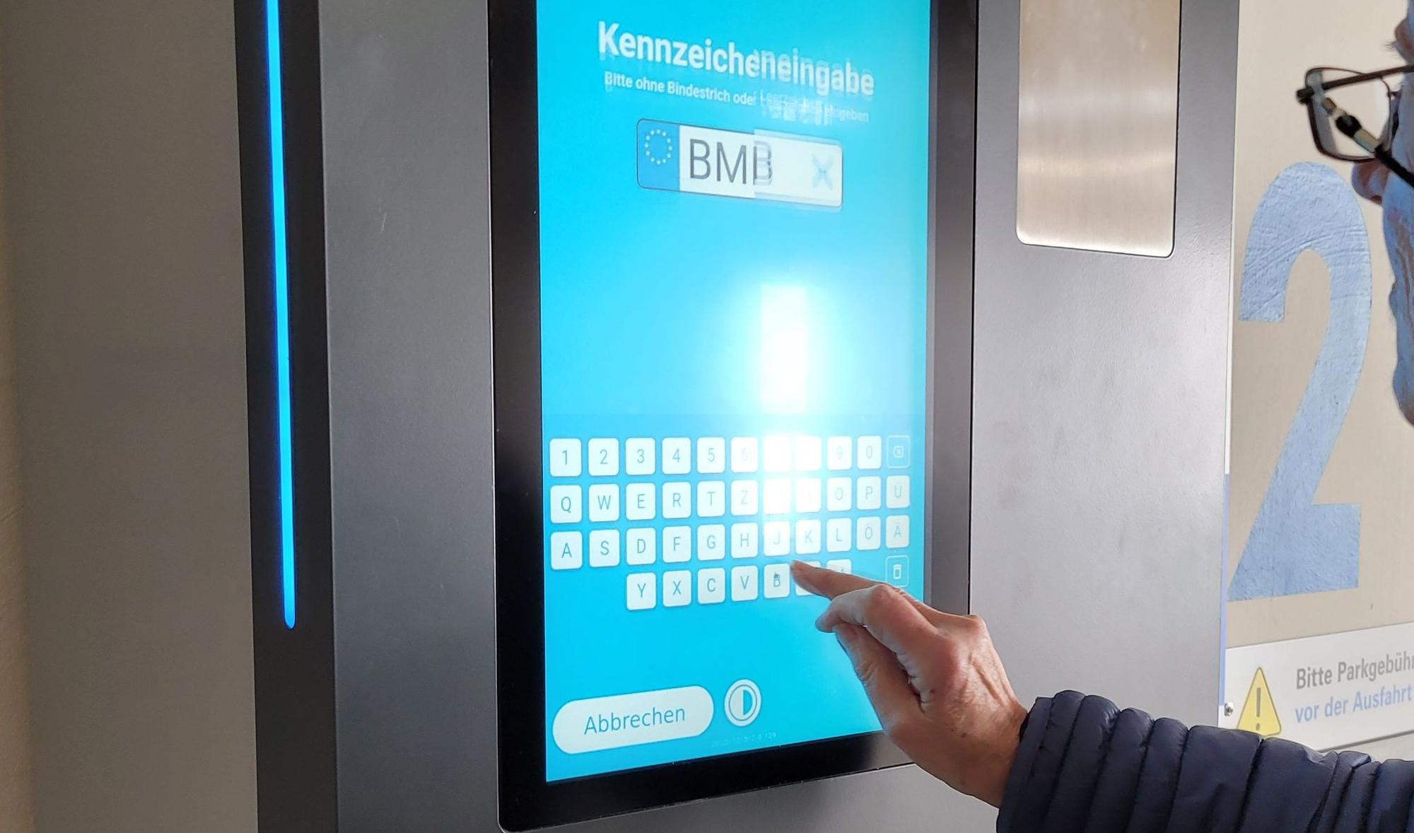 Ein Parkautomat, zu sehen sind ein Buchstabenfeld und ein Hand.