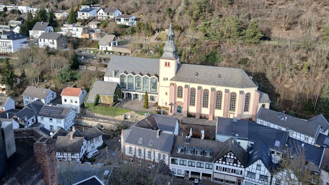 Das Bild zeigt die von Häusern umgebene Kirche und im Hintergrund Wald.