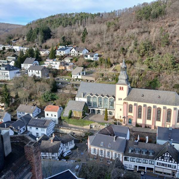 Das Bild zeigt die von Häusern umgebene Kirche und im Hintergrund Wald.