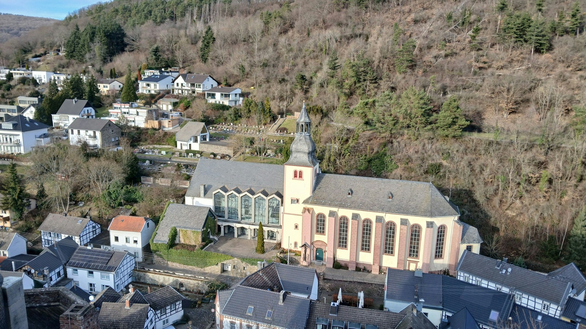 Das Bild zeigt die von Häusern umgebene Kirche und im Hintergrund Wald.