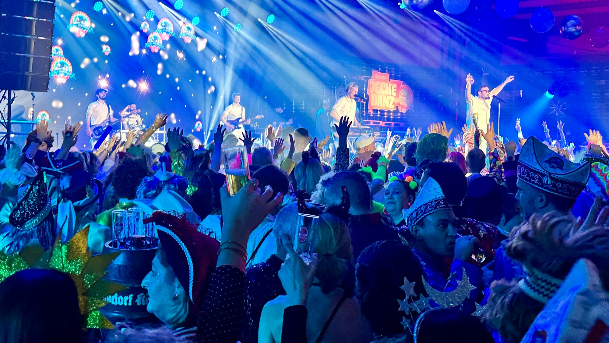 Eine Band animiert das feiernde Publikum auf einer Bühne.