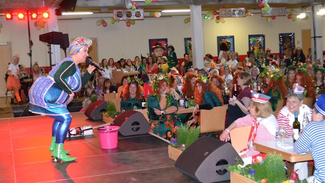 Eine Frau in grellbuntem Kostüm auf der Bühne bei einer Karnevalssitzung.