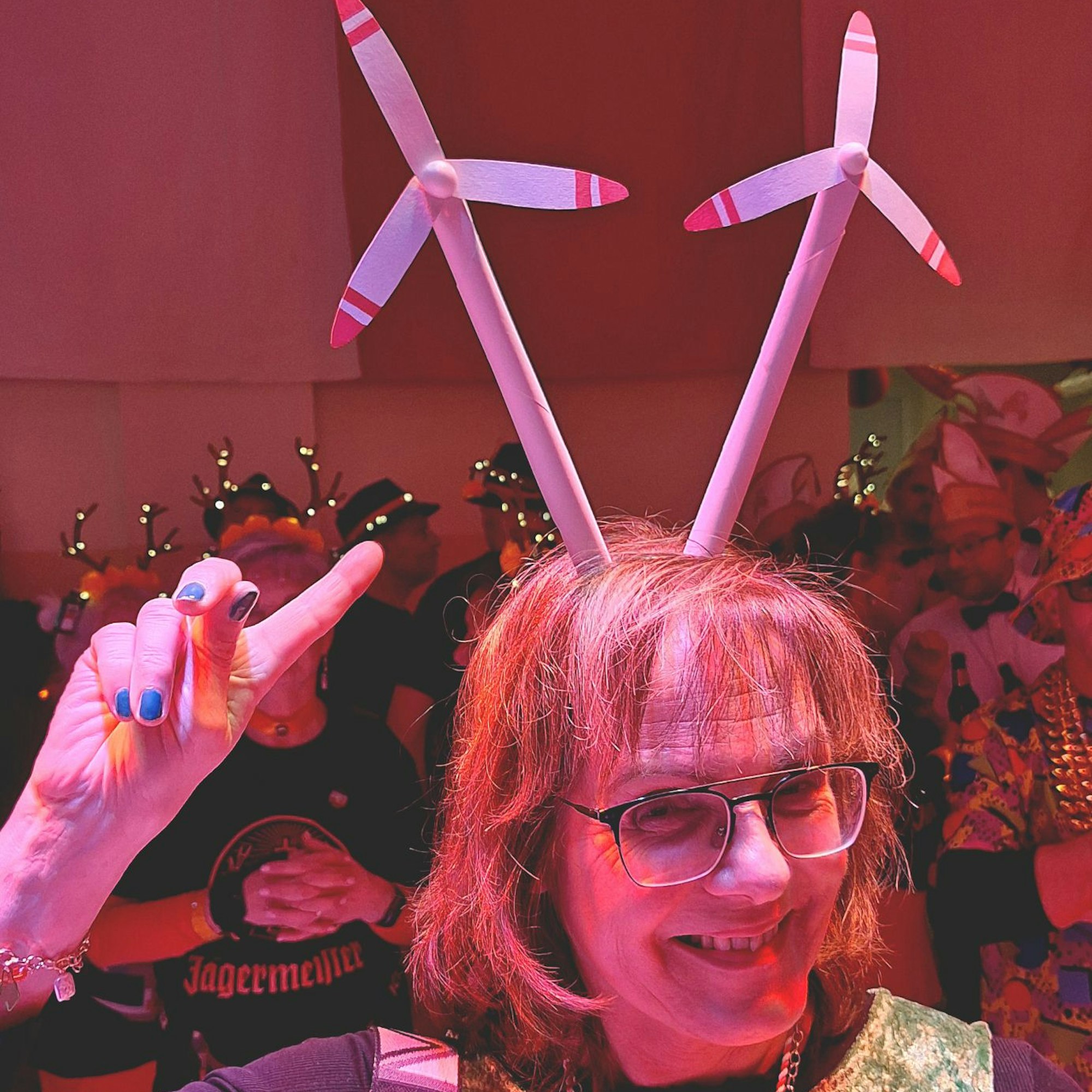 Das Bild zeigt die Obengenannte während der Sitzung. Sie zeigt auf ihre Miniatur-Windräder auf dem Kopf.