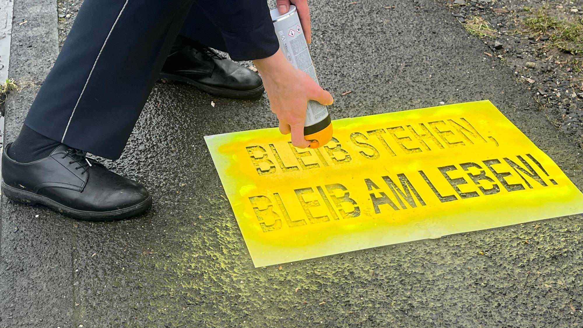 Der Schriftzug wird mit Farbe aus der Dose auf den Boden gesprüht.