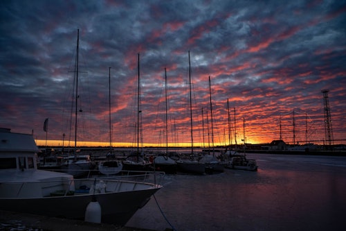03.02.2026, Mecklenburg-Vorpommern, Stralsund: Die Sonne geht über dem Stadthafen auf und taucht den Himmel über dem Strelasund vor der Insel Rügen in ein warmes Licht. Der Strelasund trennt bei Stralsund die Insel Rügen vom Festland.