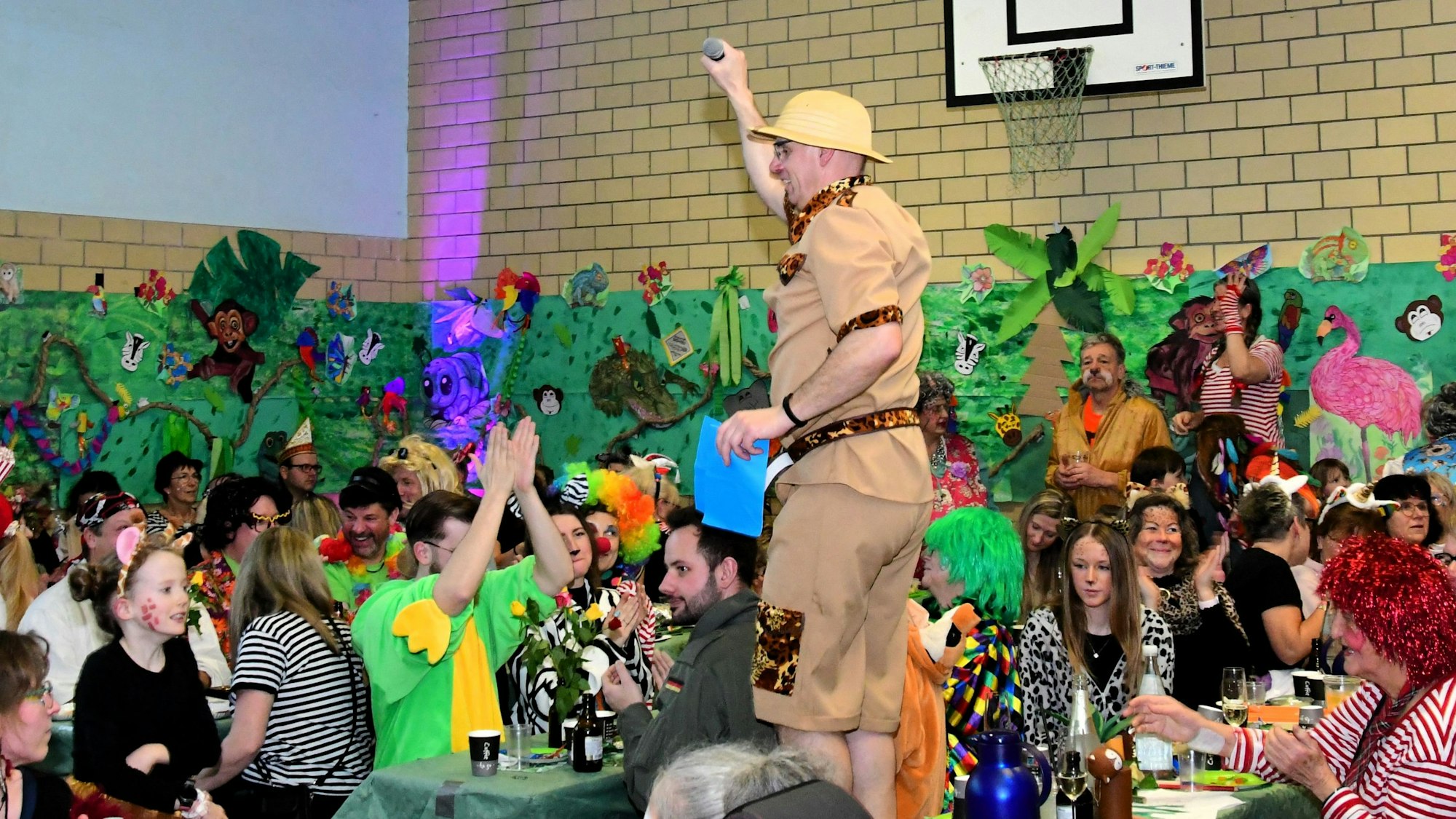 Zwischen den kostümierten Jecken steht ein Mann im Safari-Look auf dem Tisch.