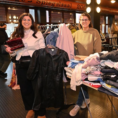 Drei Frauen stehen hinter einem Stand mit Kleidung.
