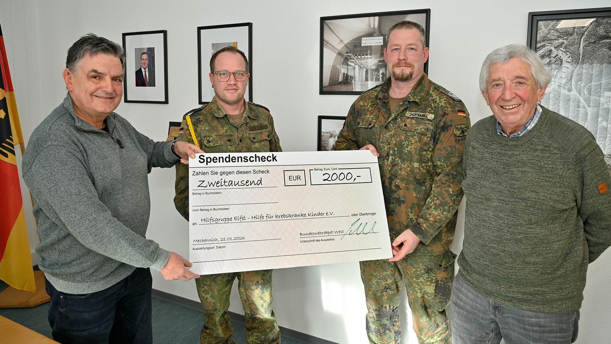 Zwei Bundeswehrangehörige in Tarnunifom überreichen einen Spendenscheck an zwei Zivilisten.