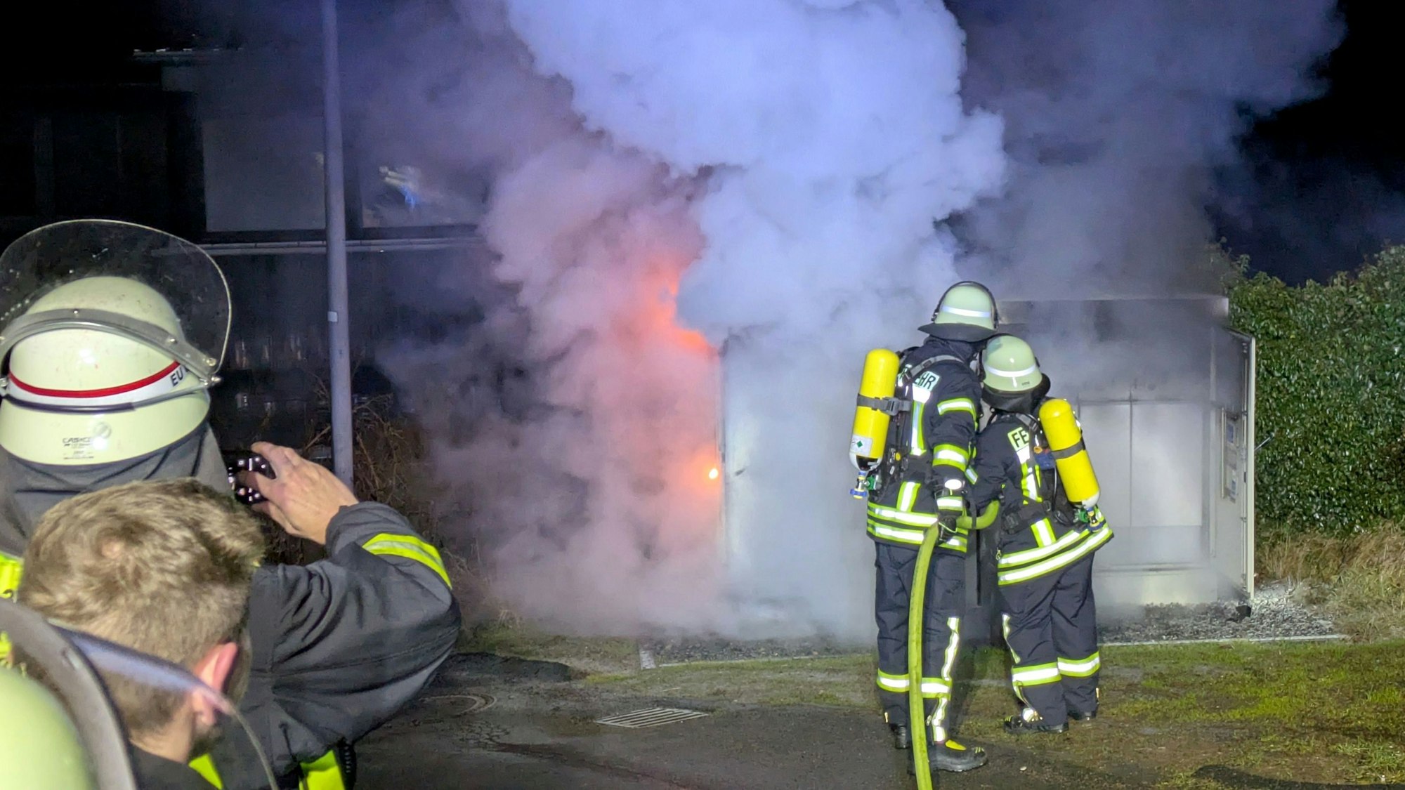 Feuerwehrleute löschen einen brennenden Trafo an der Bergstraße in Nettersheim mit Schaum.