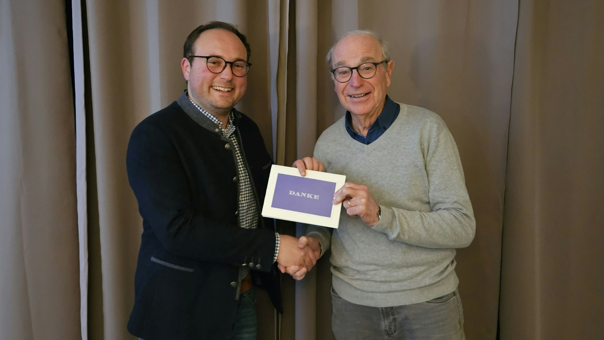 Das Foto zeigt zwei Männer, die ein Stück Papier mit der Aufschrift „Danke“ in der Hand halten.