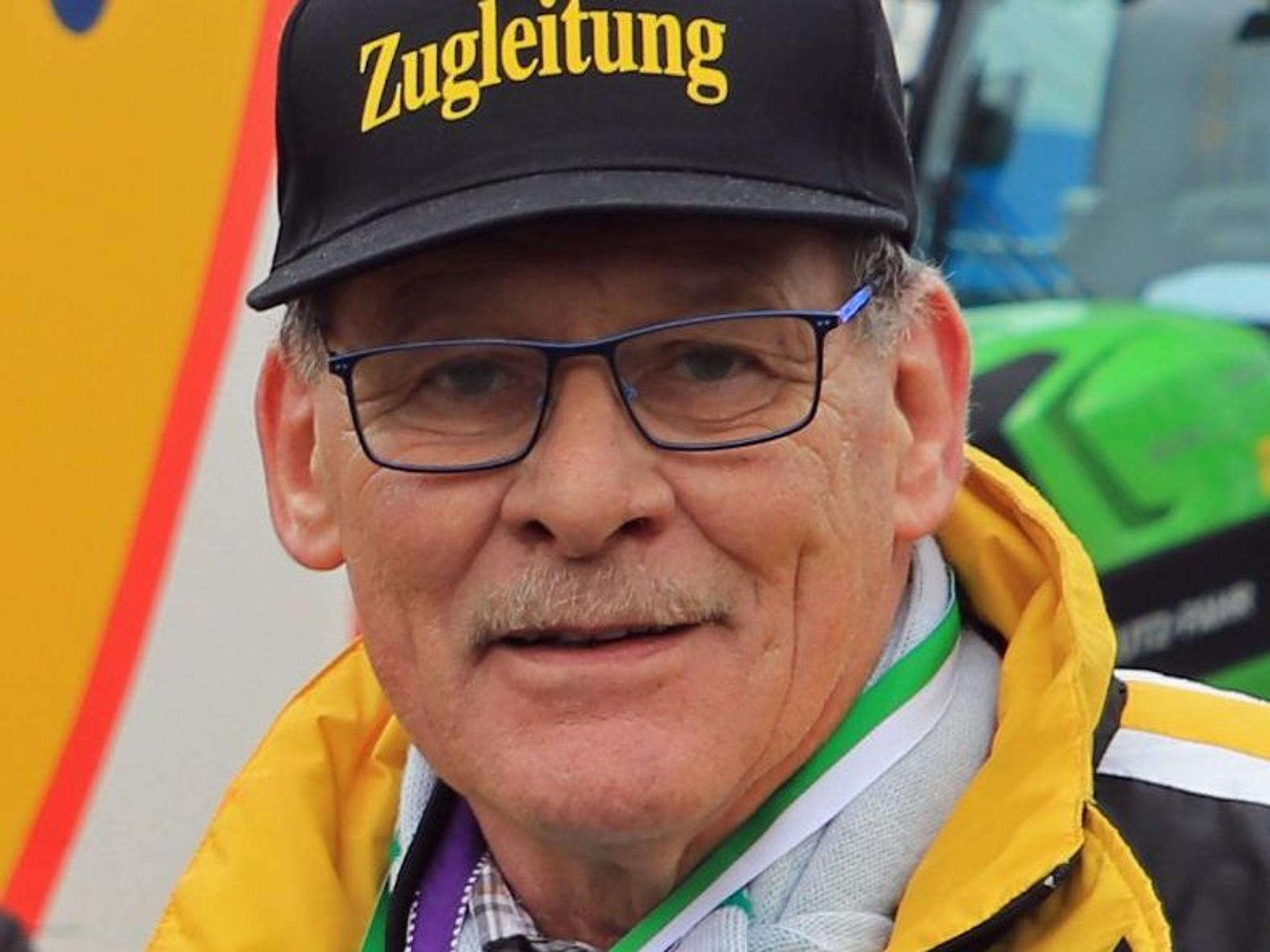 Auf dem Bild ist das Portrait eines Mannes mit Brille und Kappe zu sehen.