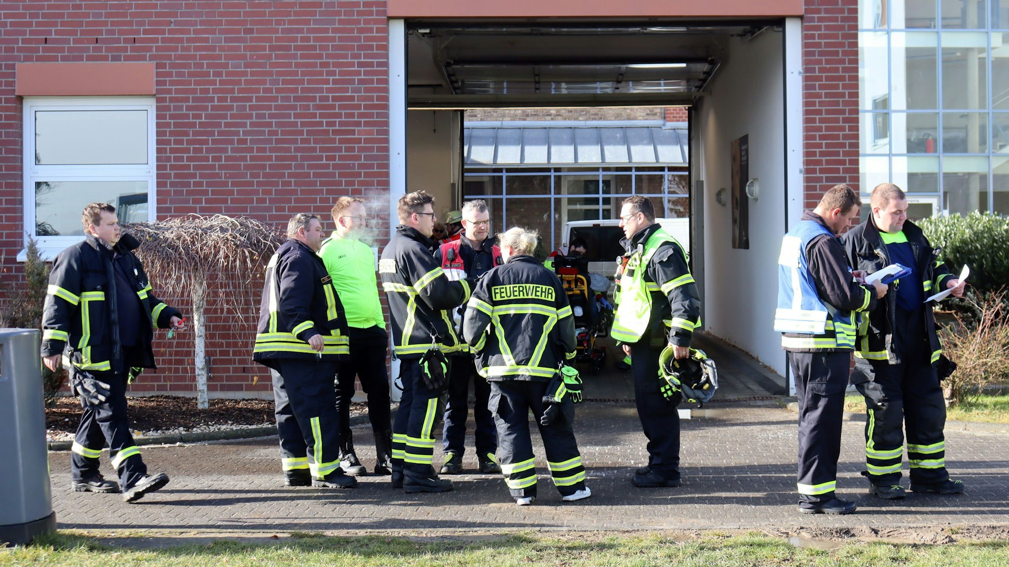 Feuerwehrleute stehen vor einem Eingang der Fachklinik.