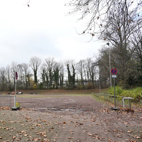 Ein alter sanierungsbedürftiger Ascheplatz. Darauf Herbstlaub.