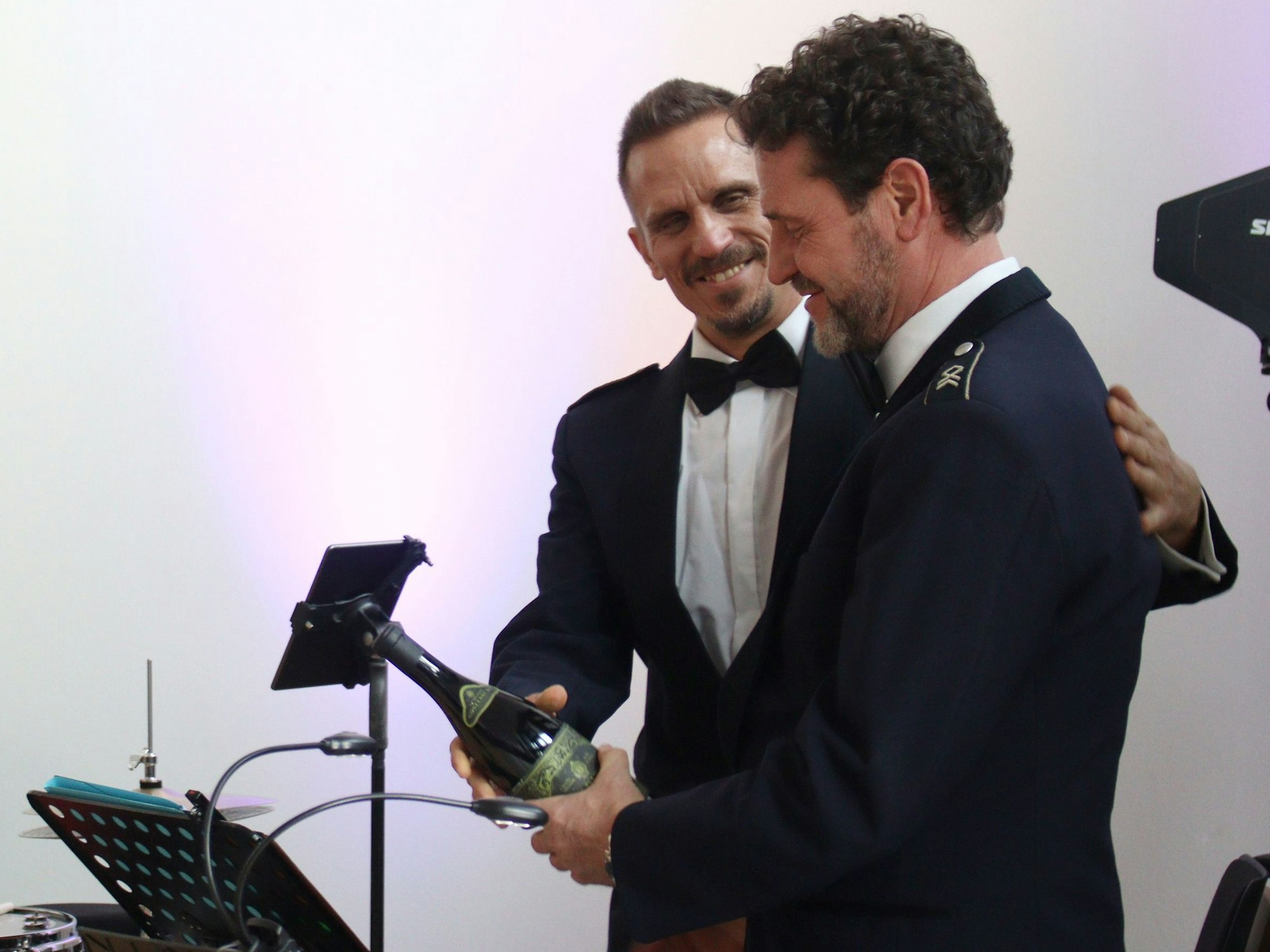 Frank Siegemund bekommt von einem Kollegen aus der Bundeswehr-Big-Band eine Flasche zum Abschied überreicht. Der Kollege legt ihm die Hand auf den Rücken.