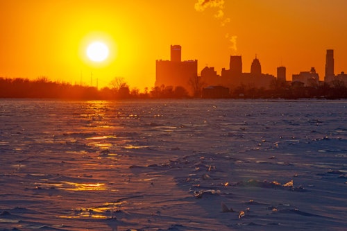 04.02.2026, USA, Detroit: Die Sonne steht tief über dem eisbedeckten Detroit River in der Nähe der Innenstadt von Detroit. Das kalte Wetter der letzten Zeit hat die Hälfte der Oberfläche der Großen Seen mit Eis bedeckt, einschließlich fast des gesamten Eriesees, der stromabwärts von Detroit liegt.