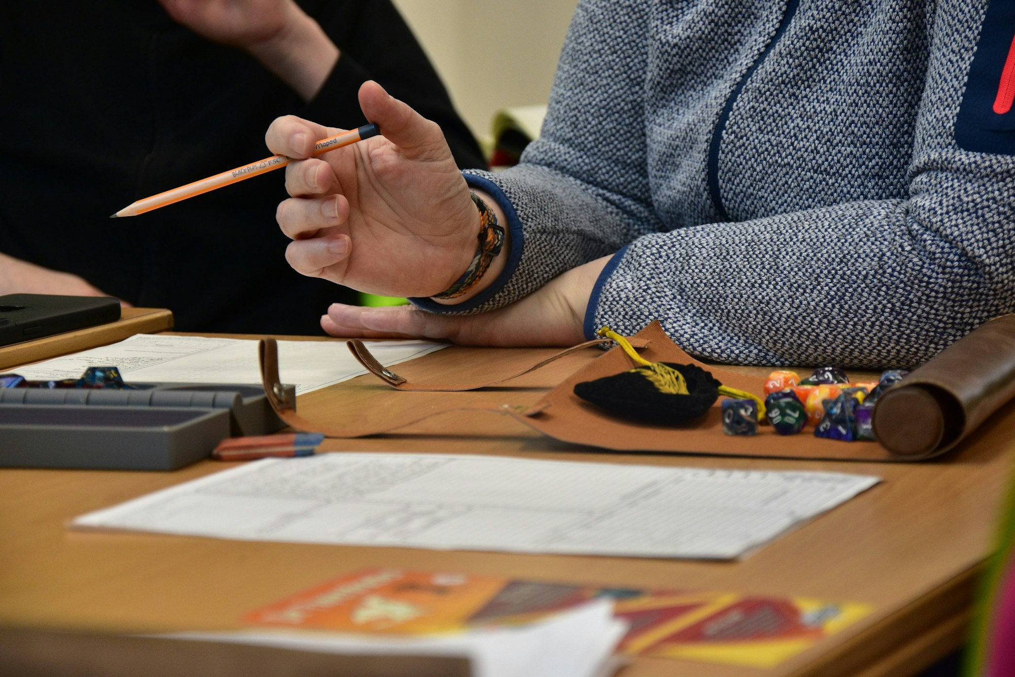 Block, Würfel und eine Person mit Bleistift an einem Tisch.