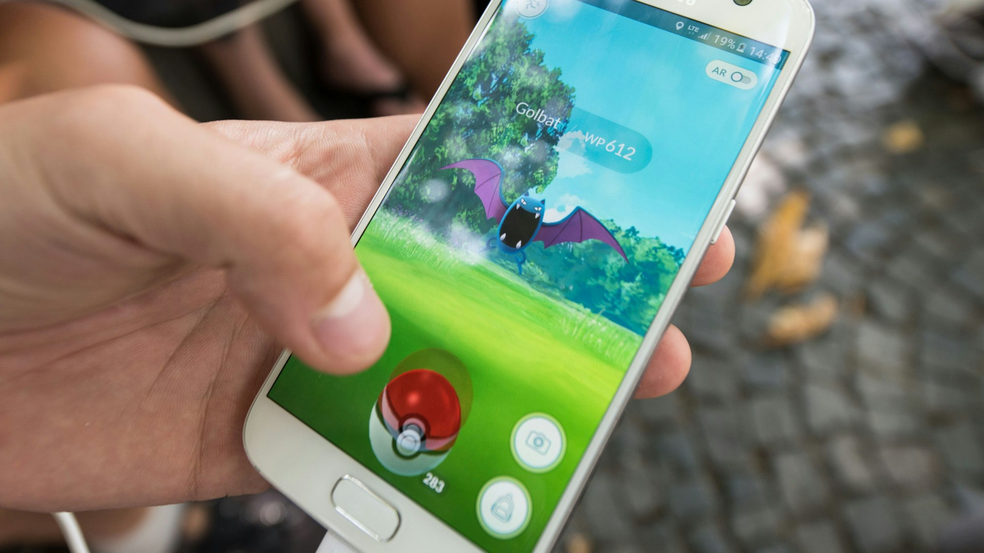 Eine Person hält ein Handy in der Hand und spielt Pokémon Go.