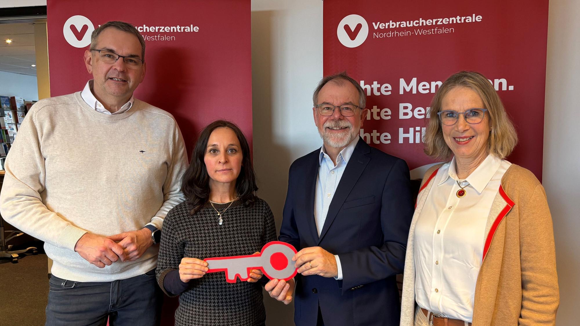 Ein Mann und eine Frau halten gemeinsam einen großen Pappschlüssel in den Händen. Alle lachen in die Kamera.