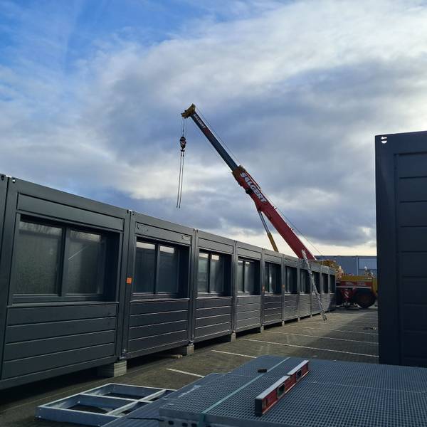 Die Aufnahme zeigt Container neben denen ein Kranwagen steht.