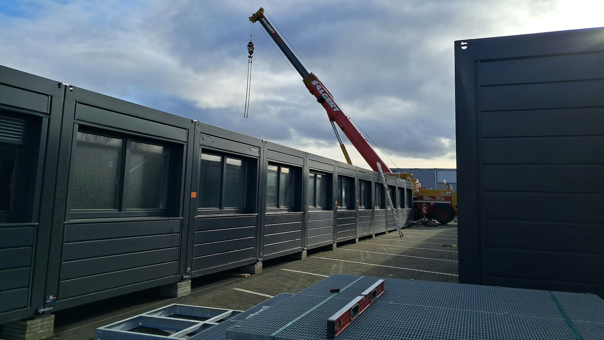 Die Aufnahme zeigt Container neben denen ein Kranwagen steht.