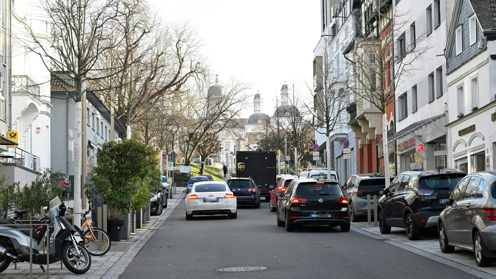 Zwei Autos parken in zweiter Reihe. Zwei Fahrer versuchen, daran vorbeizukommen.