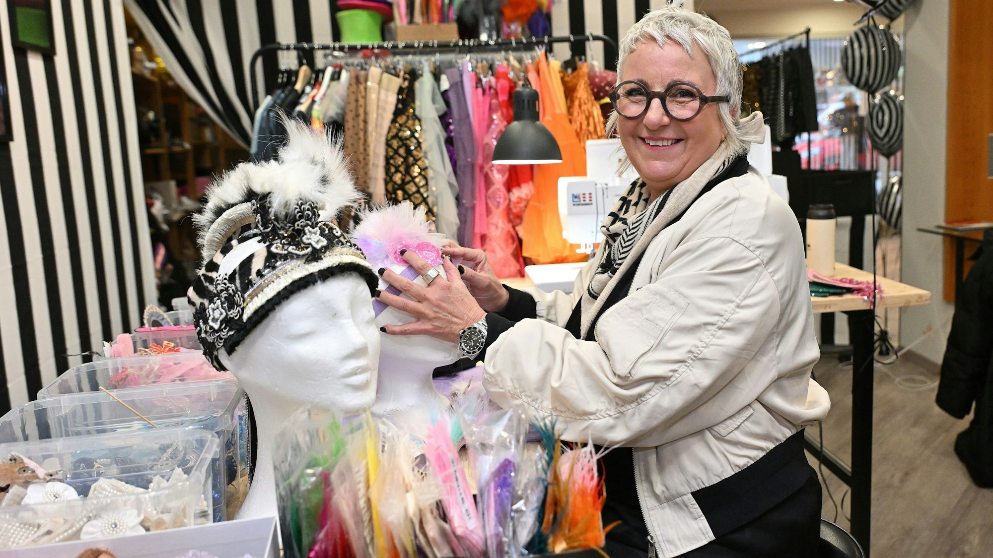 Eine Frau mit schwarzer Brille steht in einem Laden mit Karnevalskleidung.