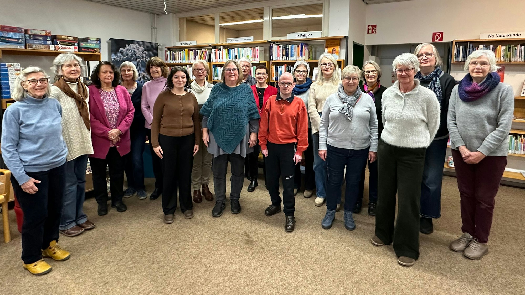 Das Overather Stadtbüchereiteam steht vor Regalen mit Büchern in der Stadtbibliothek.