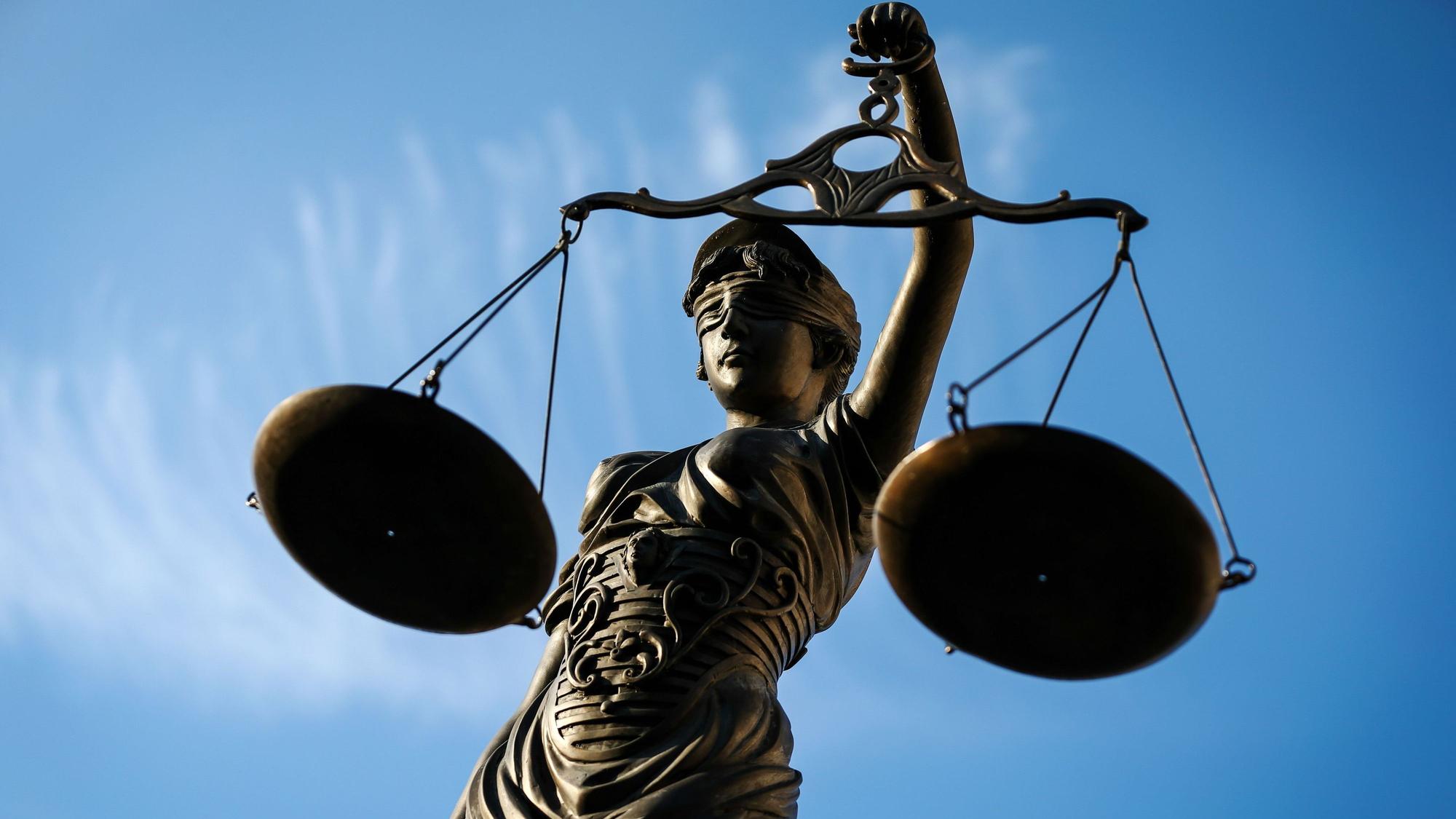 Eine Statue der Justitia aus Bronze, vor blauem Himmel, hält eine Waage in der Hand. (Symbolbild)