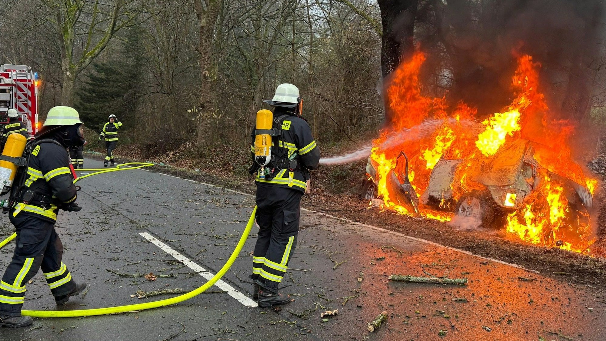 Das Bild zeigt Einsatzkräfte der Feuerwehr Lindlar beim Löschen des brennendes Pkw-Wracks.