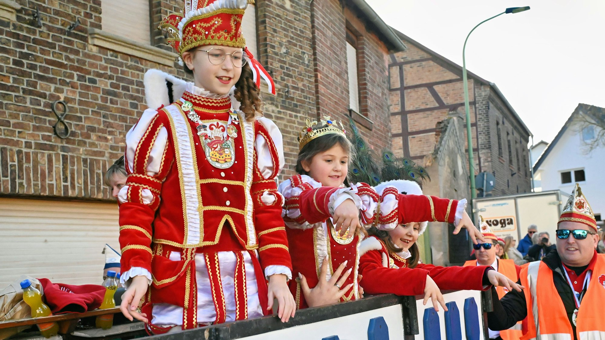 Prinz Isabella I. (Marian), Jungfrau Greta (Hamacher) und Bauer Mia (Hamacher) stehen kostümiert auf einem Karnevalswagen.