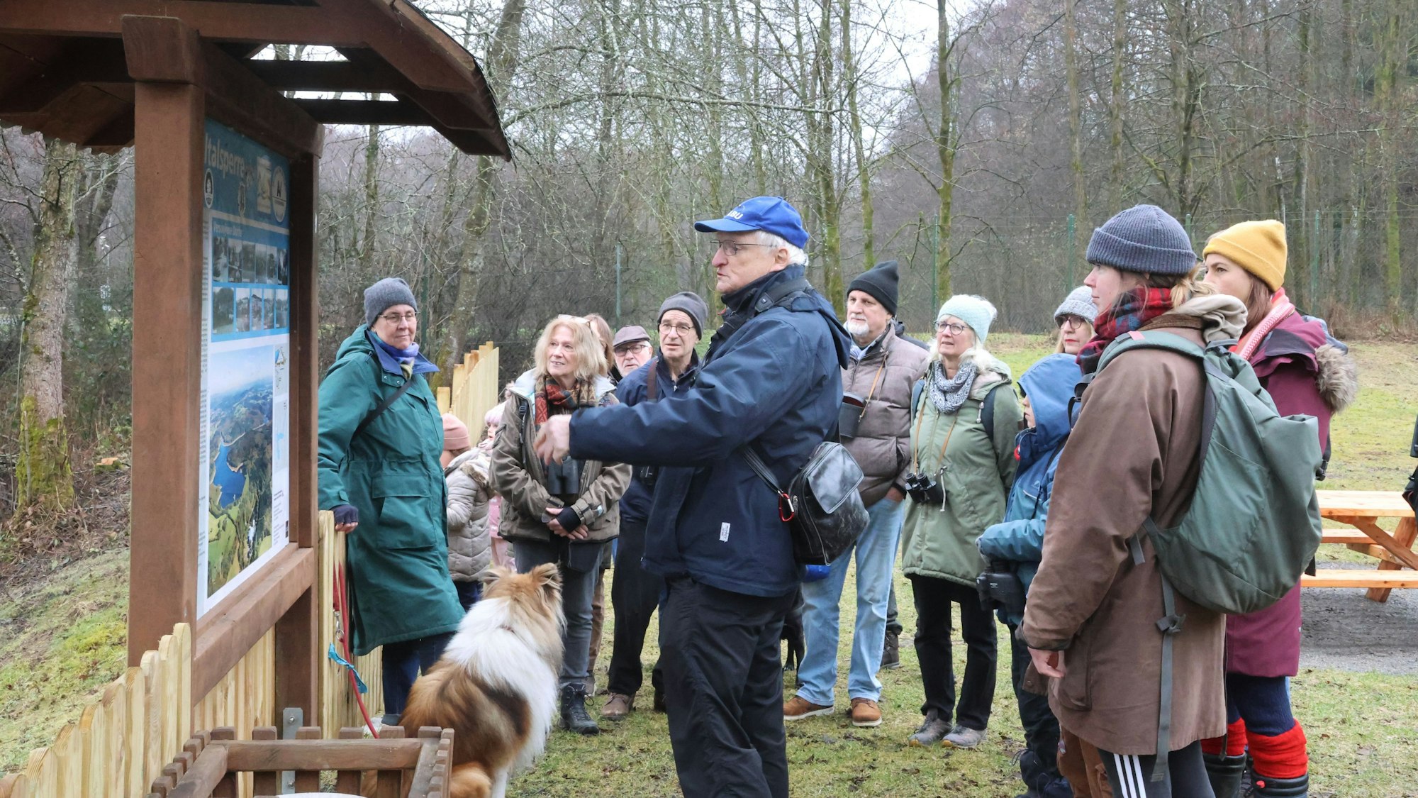 Eine Gruppe steht vor einer Infotafel in der Natur.