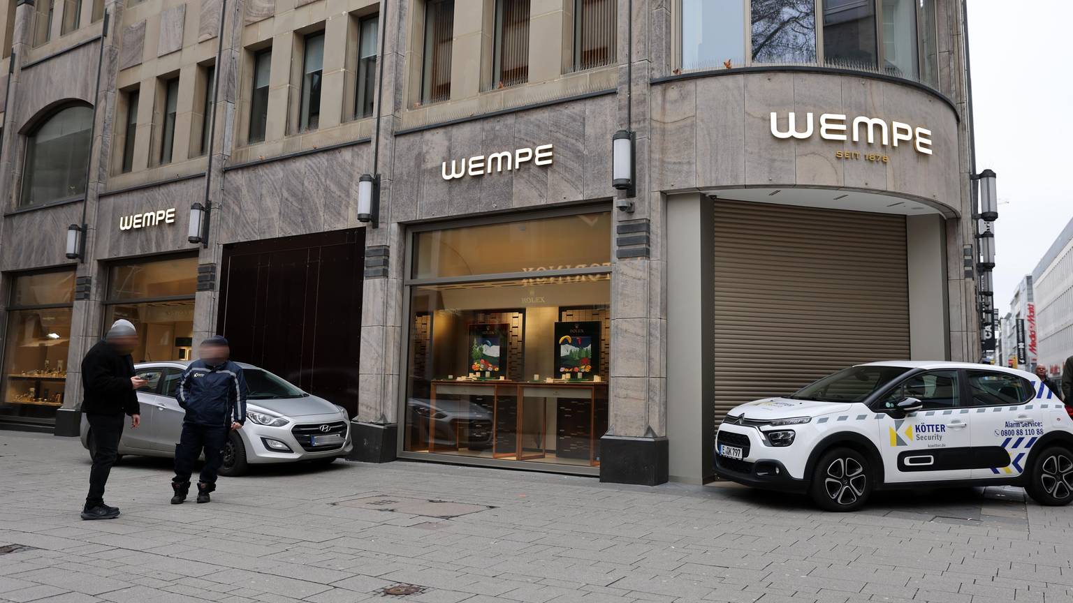 Ein Auto steht vor dem beschädigten Schaufenster des Juweliergeschäfts, das mit einer dunklen Holzplatte verschlossen wurde