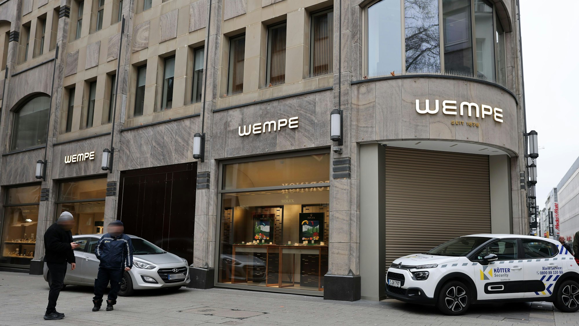 Ein Auto steht vor dem beschädigten Schaufenster des Juweliergeschäfts, das mit einer dunklen Holzplatte verschlossen wurde