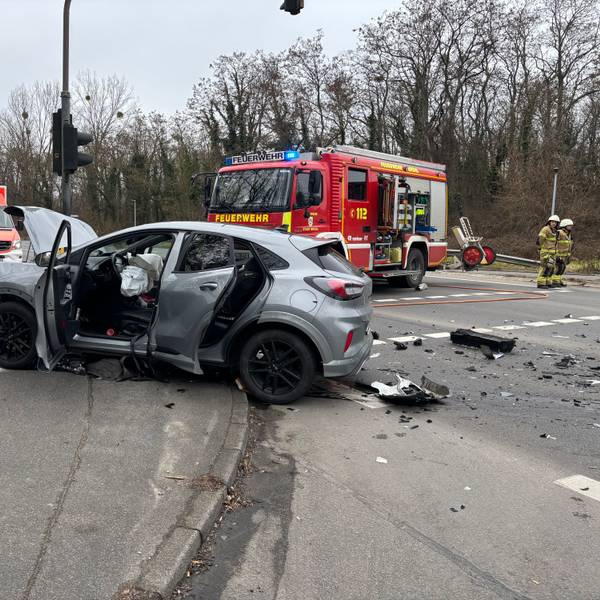 Im Vordergrund ein Fahrzeug mit Unfallspuren. Gas- und Fahrzeugsplitter lagen weit über die Kreuzung verteilt. Im Hintergrund Feuerwehr- und Notarztfahrzeuge.