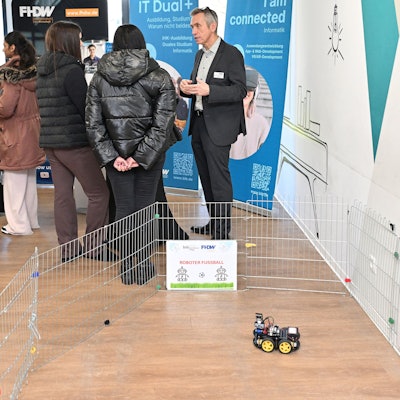 Besucher sprechen in den Räumlichkeiten der Fachhochschule mit Dozierenden.