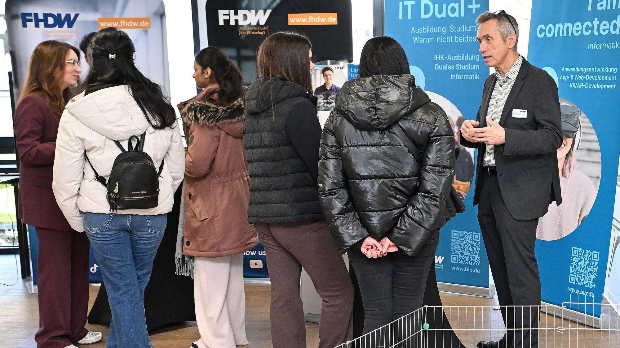Besucher sprechen in den Räumlichkeiten der Fachhochschule mit Dozierenden.
