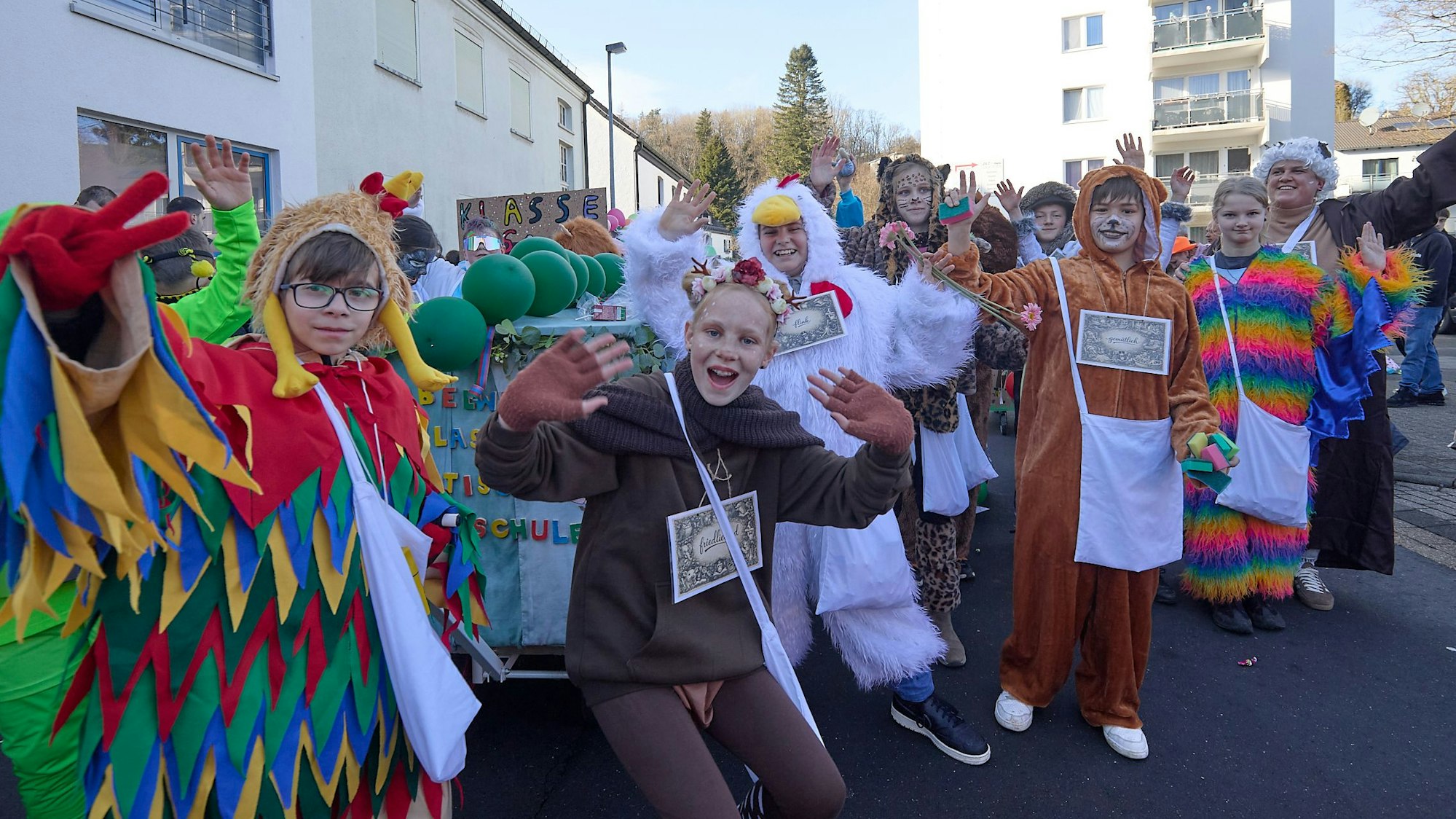 Verkleidete Kinder heben die Hände und machen fröhliche Gesichter.