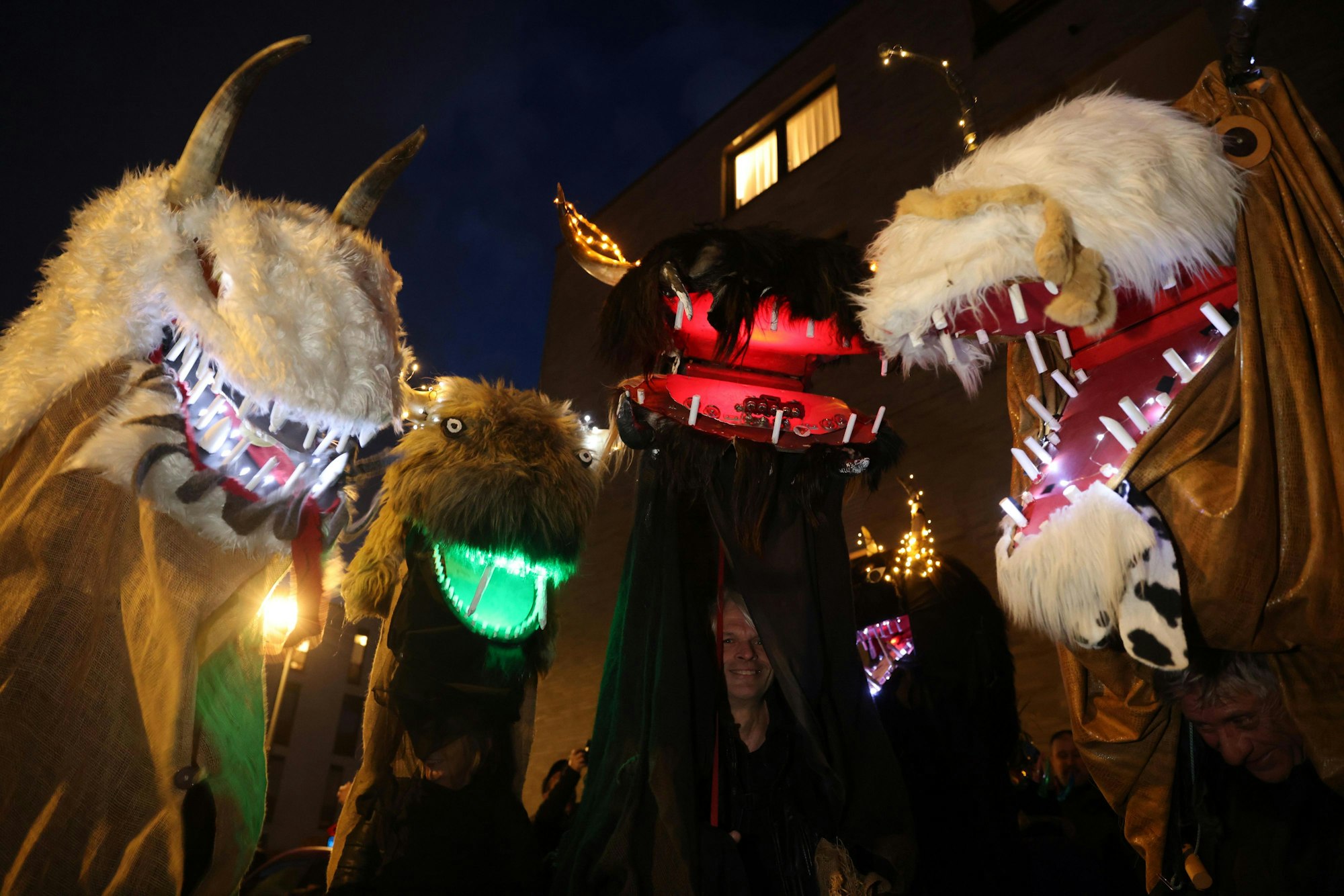 Drei Kostüme auf dem Geisterzug. Fellige Wesen mit scharfen Hörnern und Zähnen, die Mäuler sind aufgerissen und leuchten.