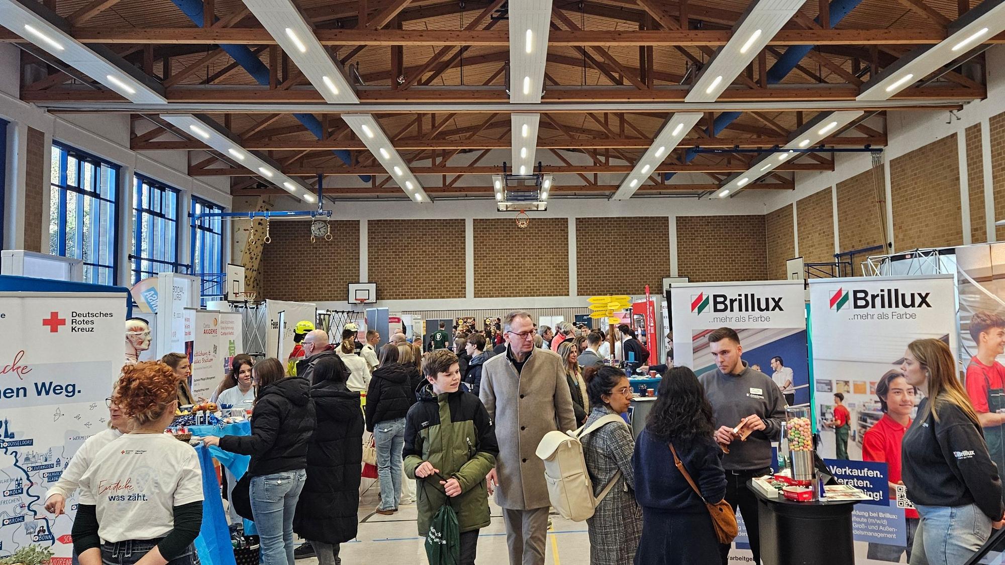 Besucherinnen und Besucher informieren sich auf der Ausbildungsbörse in einer Sporthalle.