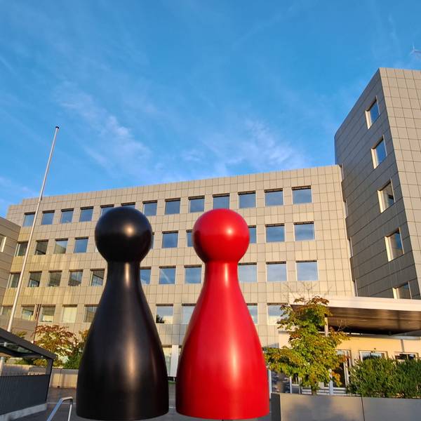 Eine schwarze und eine rote Spielfigur stehen vor dem Kreishaus des Rheinisch-Bergischen Kreises in Bergisch Gladbach-Heidkamp.