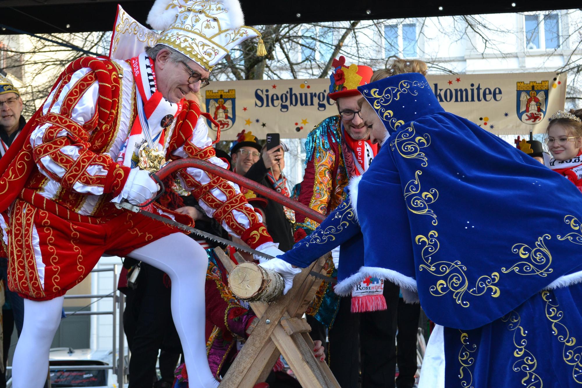 Prinz Helmut IV. und Siegburgia Elke I. durchtrennen einen Baumstamm als wäre es Butter.
