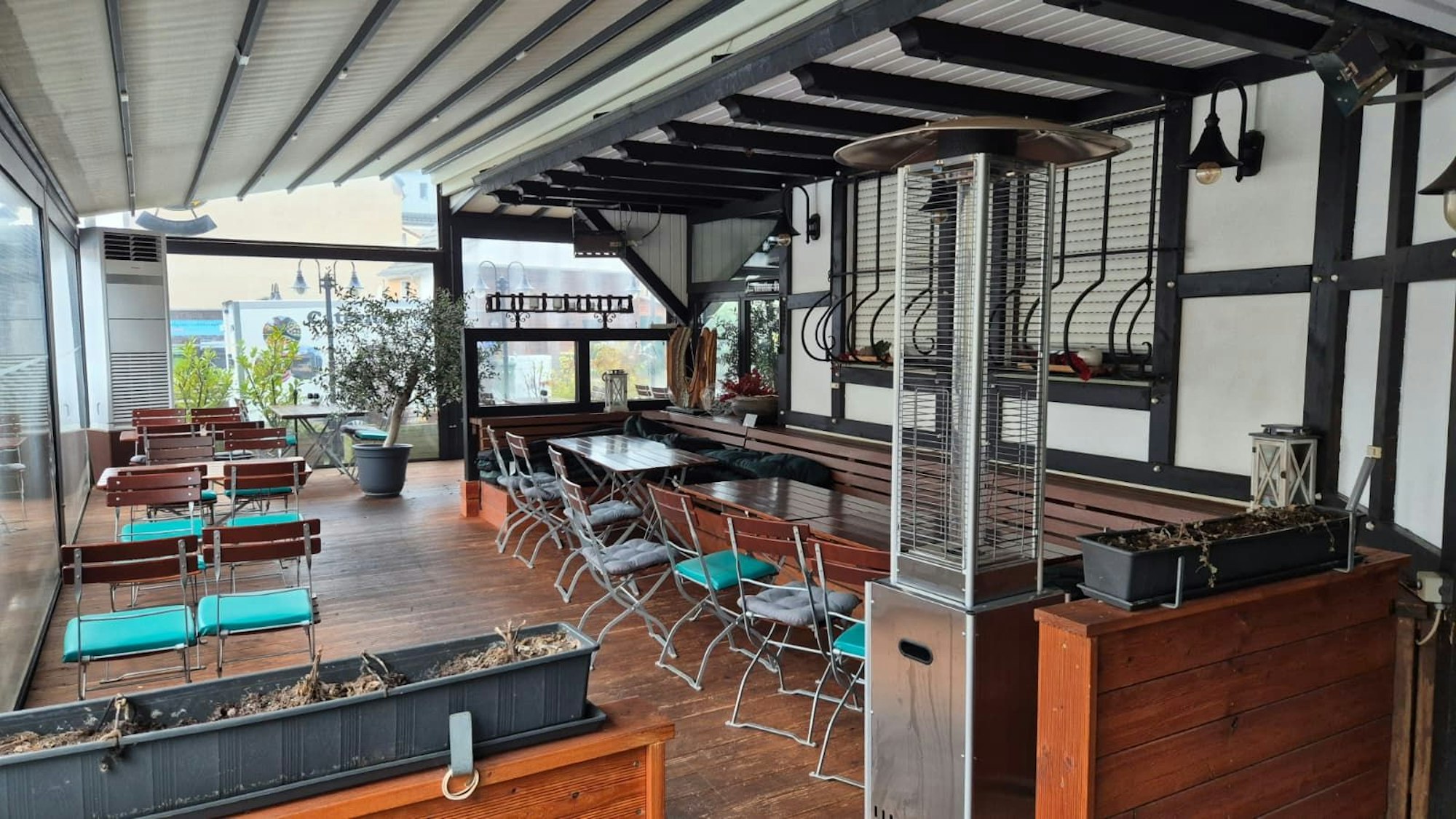 In einem verglasten Anbau stehen leere Tische und Stühle eines Restaurants.