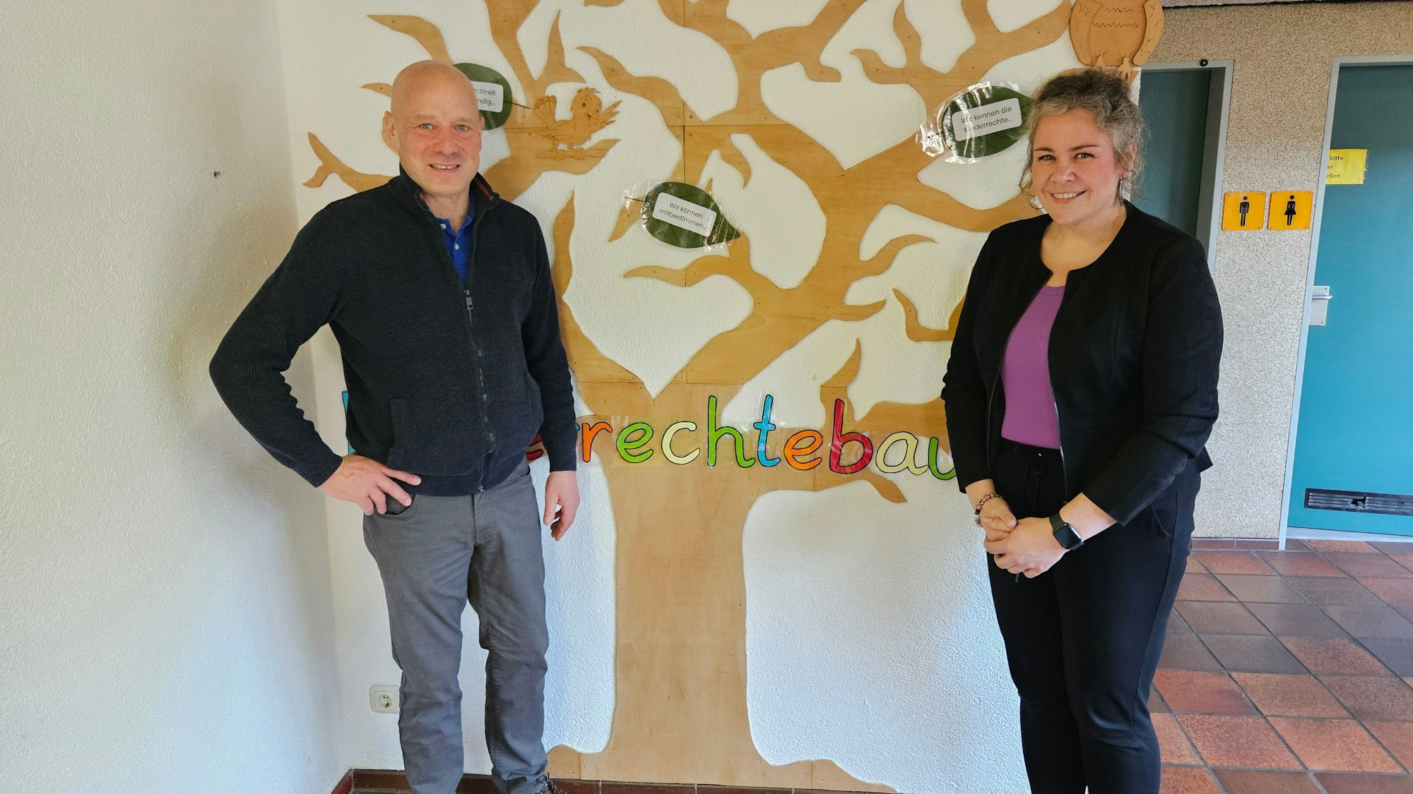Thomas Müller und Yvonne Schäfer stehen vor dem gemalten Kinderrechtebaum.