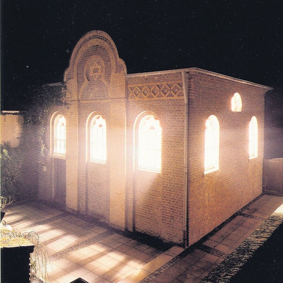 Zu sehen ist eine hell erleuchtete Synagoge.
