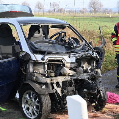 Das Bild zeigt einen verunfallten Kleinwagen am Straßenrand.
